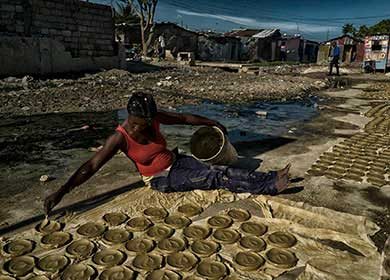 An impoverished Haitian woman making clay cakes. Courtesy of the United Nations and Logan Abassi.