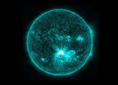 A filtered image of the sun comprised of teal wavelengths of light. The image is displaying a large sun spot. Courtesy of NASA.
