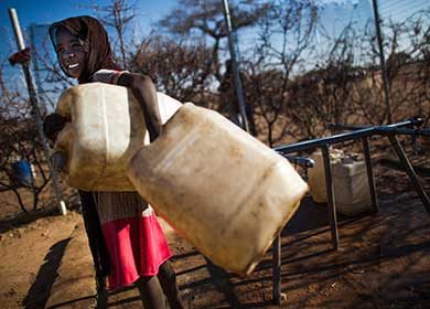 A young girl carries two water cans in the Al Shaddad camp in North Darfur. Courtesy of the United Nations and Albert González Farran.
